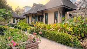 A traditional-style building with a tiled roof and multiple windows, surrounded by lush greenery and flowering plants. - Botany Beach Resort Pattaya (Sattahip)