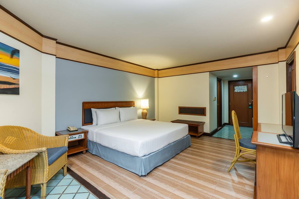 Una habitación de hotel con cama, una silla, un escritorio y televisor.