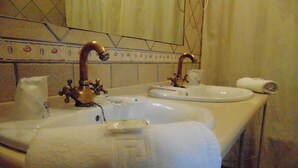 Een badkamer met twee wastafels, een handdoekrek en een toilet.