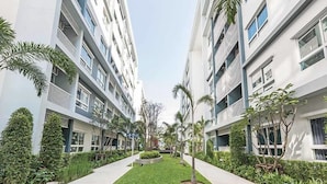 A modern apartment building with multiple floors, balconies, and a central courtyard with greenery. - The Trust Huahin Condo Garden View by Dome (Hua Hin)