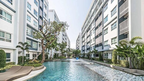 A modern hotel with a central swimming pool, surrounded by lush greenery and tall buildings. - The Trust Huahin Condo Garden View by Dome (Hua Hin)