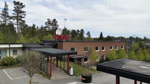 Un hôtel avec une enseigne rouge, un espace extérieur abrité et un parking.