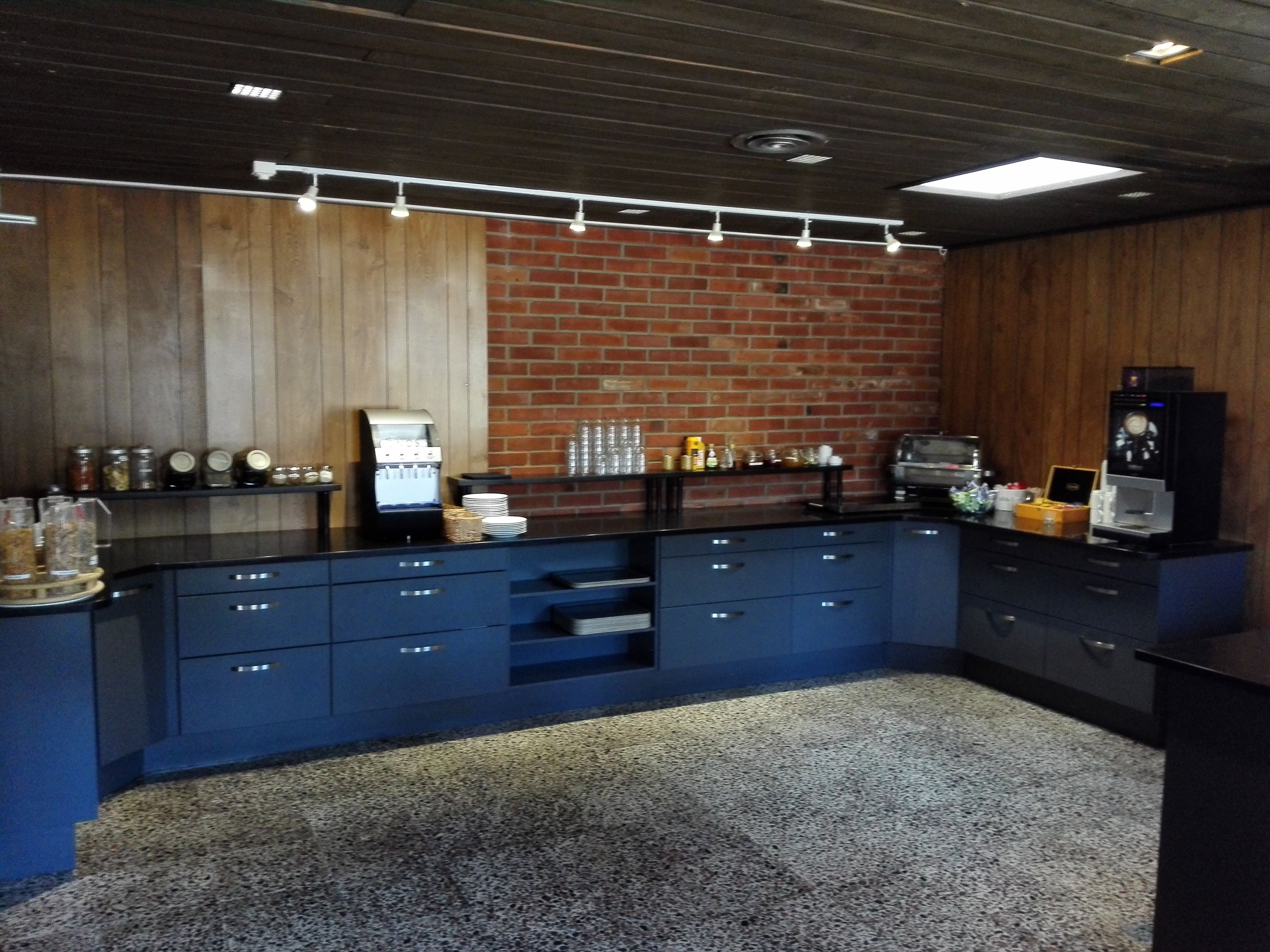 Una cocina con pared de ladrillo, armarios de madera y una máquina de café.