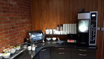 Una zona de cocina con cafetera, tostadora y varios recipientes de alimentos en la encimera.