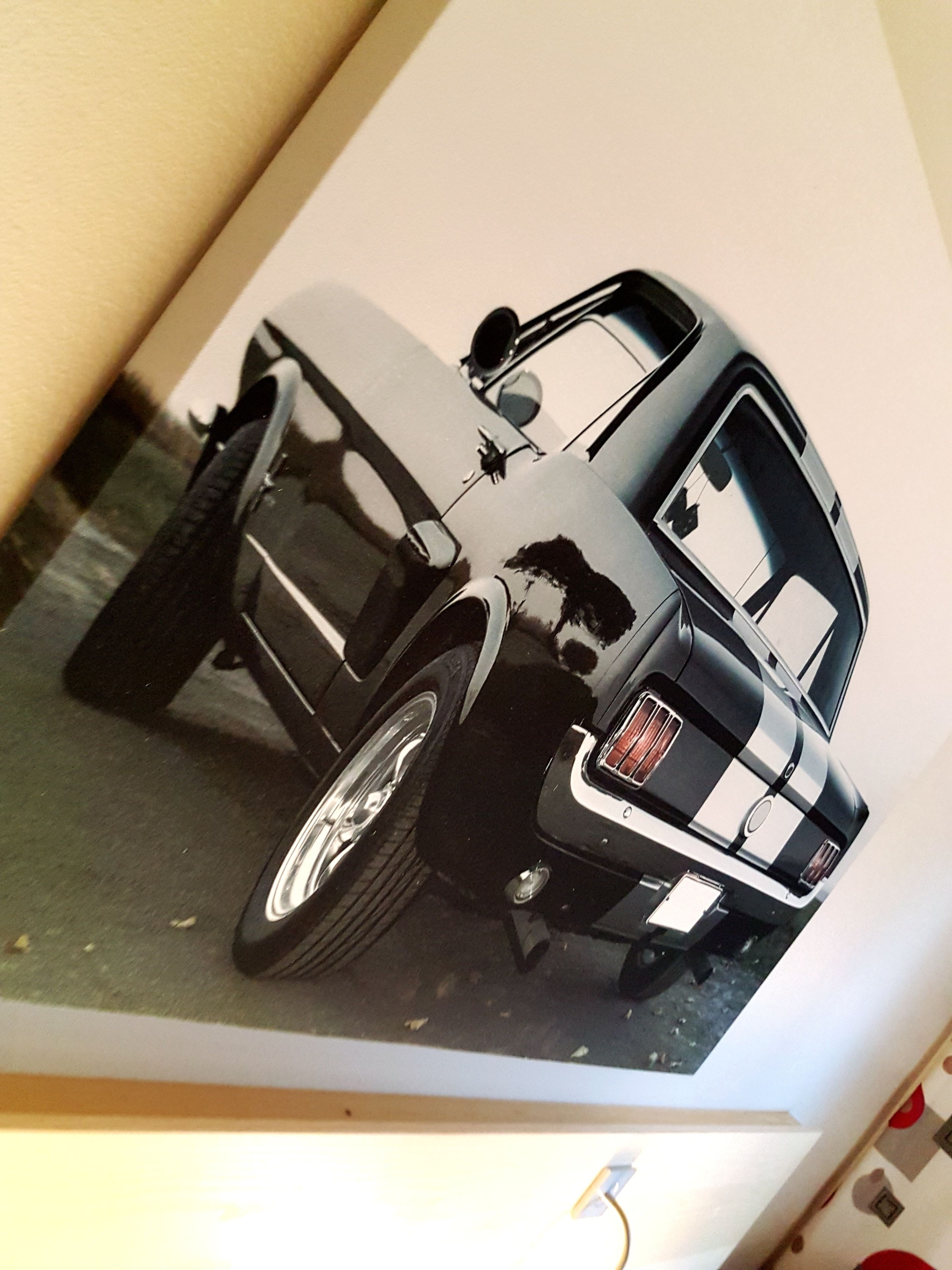 En svart bil står parkerad inomhus, och man kan tydligt se bilens baksida, inklusive baklyktorna och registreringsskylten.