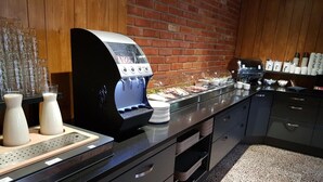Un espace cuisine équipé d’une machine à café, d’un buffet et d’un mur en briques.