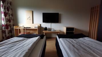 Een hotelkamer met twee bedden, een bureau, een stoel, een televisie en een klein kastje.