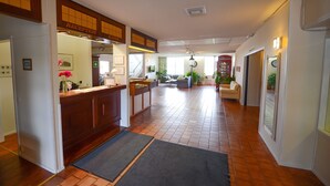 A reception area with a reception desk, a staircase, and a seating area with a sofa and chairs. - Hotel Sea Front (Raseborg)