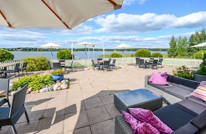 Un patio al aire libre con asientos, sombrillas y vistas al lago.