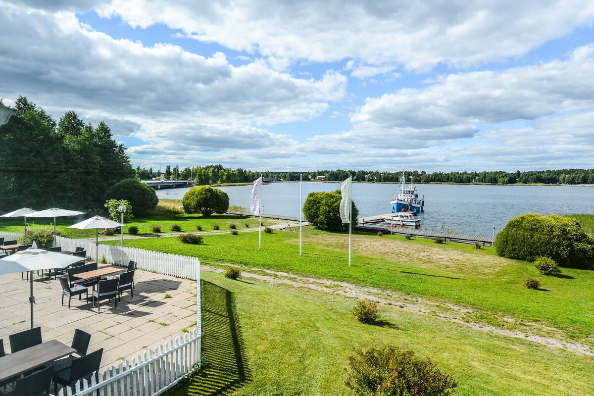 Un patio junto al lago con mobiliario exterior y vistas a un lago y un bote.