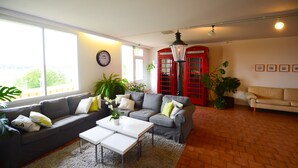 A living room with a grey sofa, white coffee table, and red telephone booths. - Hotel Sea Front (Raseborg)