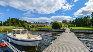 A boat docked at a wooden pier with a hotel in the background. - Hotel Sea Front (Raseborg)