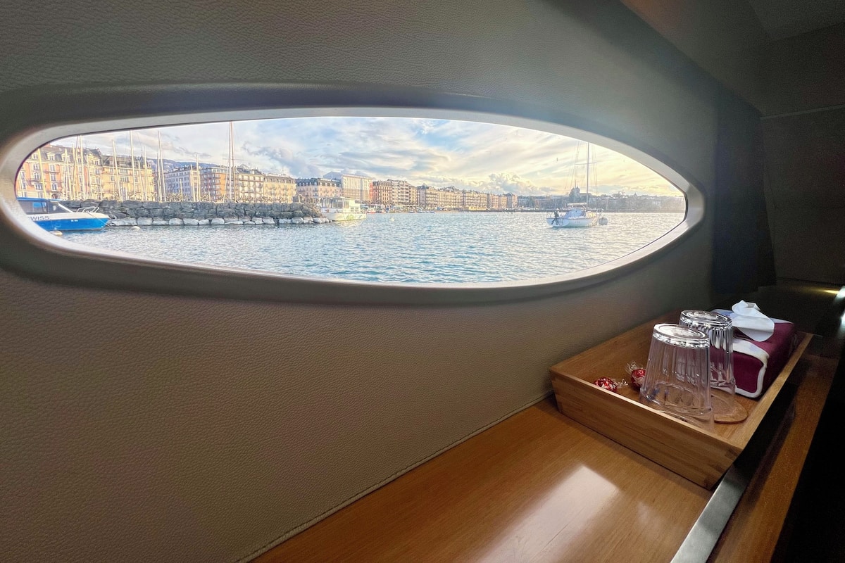 Blick aus einem Fenster auf einem Boot, mit Blick auf eine Marina mit Booten und Gebäuden.
