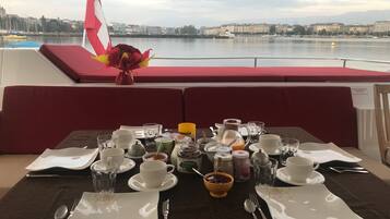 A table set for breakfast on a boat with a view of a cityscape across the water.