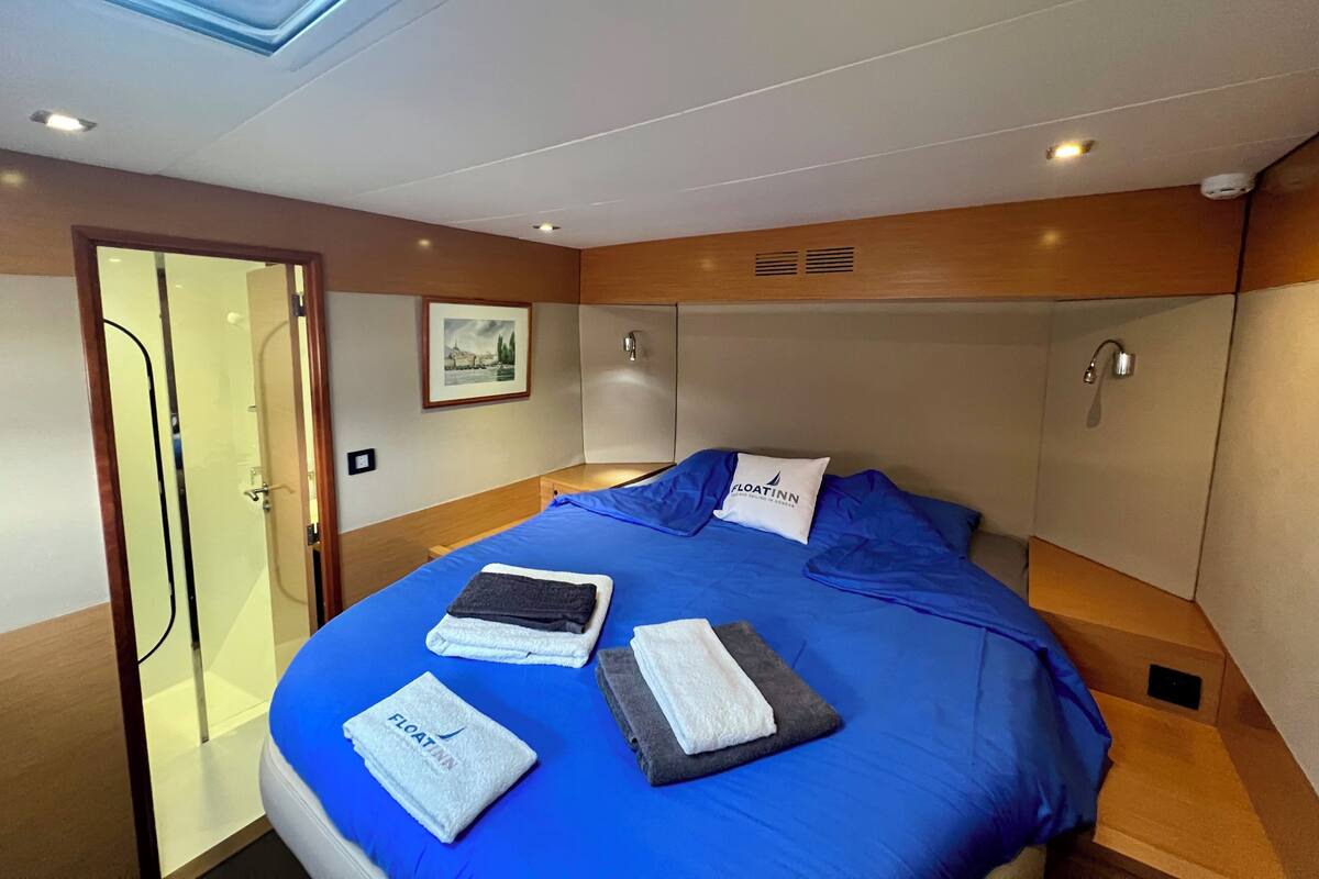 Ein modernes Hotelzimmer mit einem großen Bett, einem Oberlicht, einer Dusche und einem gerahmten Bild an der Wand.