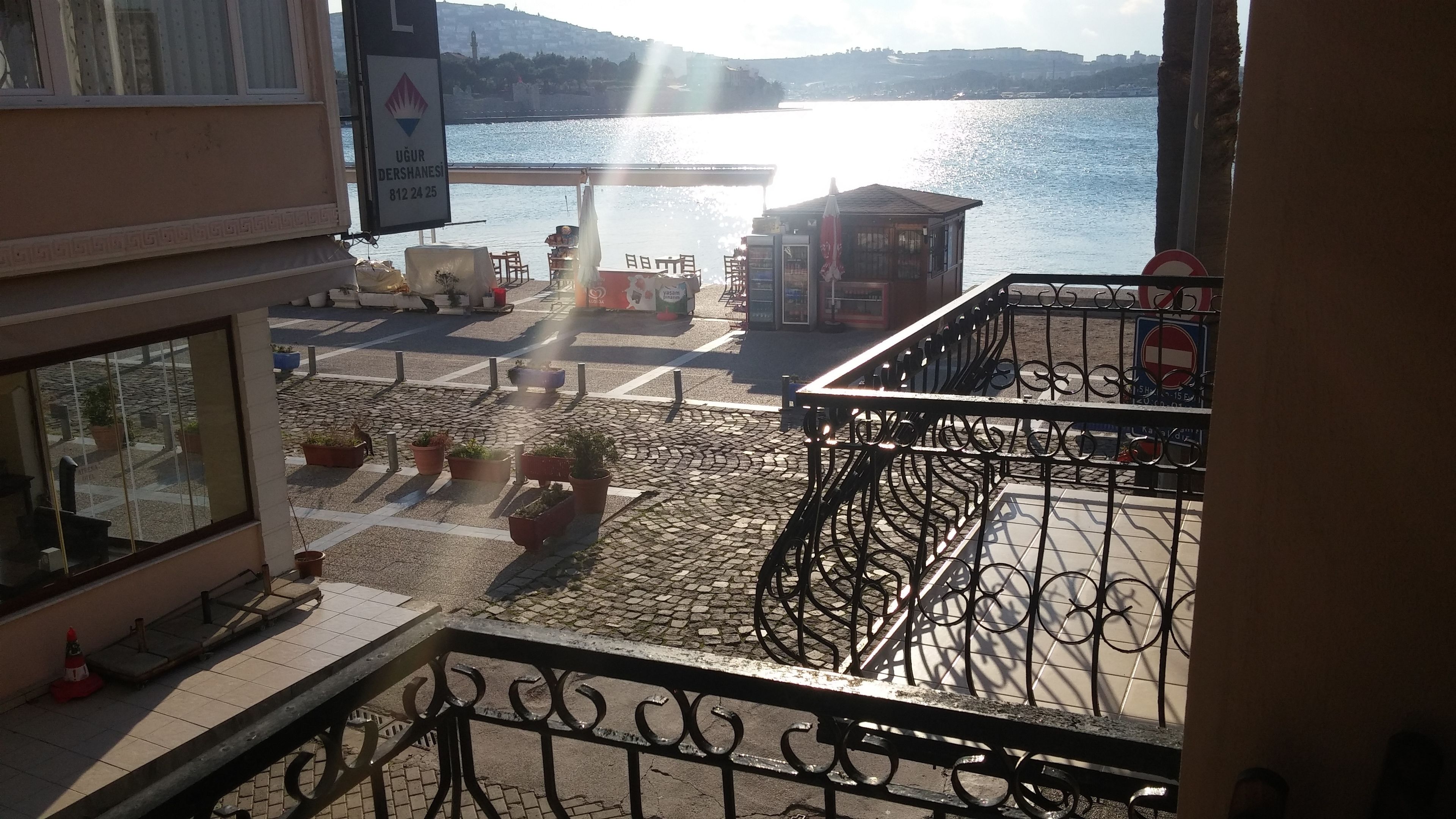 A view from a balcony overlooking a waterfront area with a café and outdoor seating.