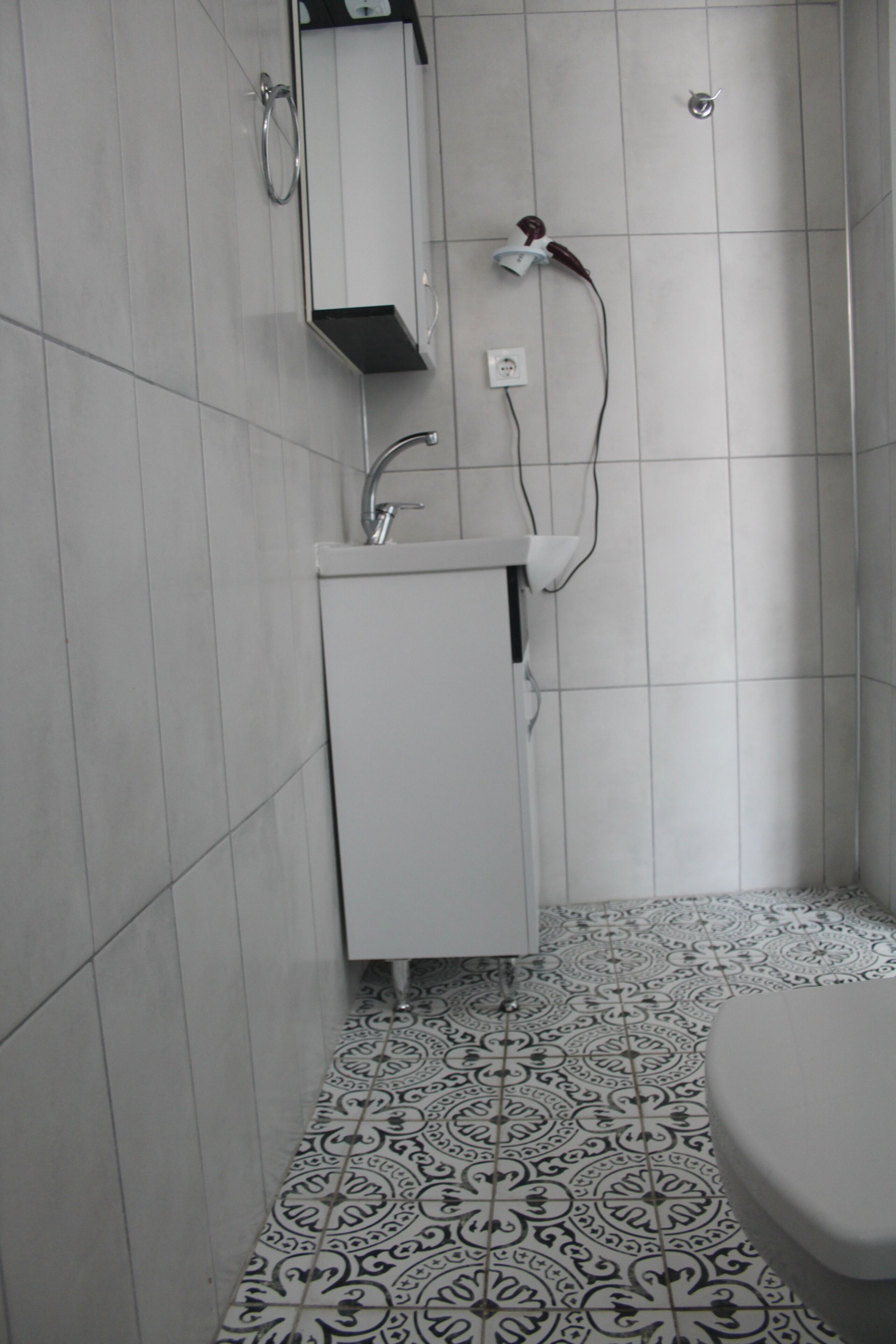 Un baño con lavamanos, espejo y baldosas de suelo con diseño.