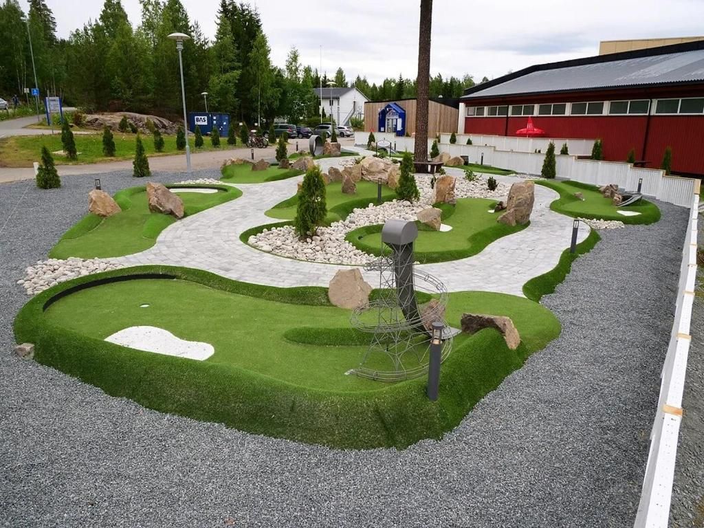 A landscaped garden area with a winding path, rock formations, and a metal sculpture.