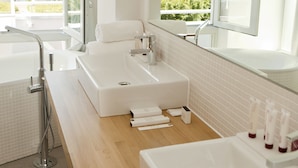 A modern bathroom with a large bathtub, a separate shower area, and a vanity with a sink and mirror.