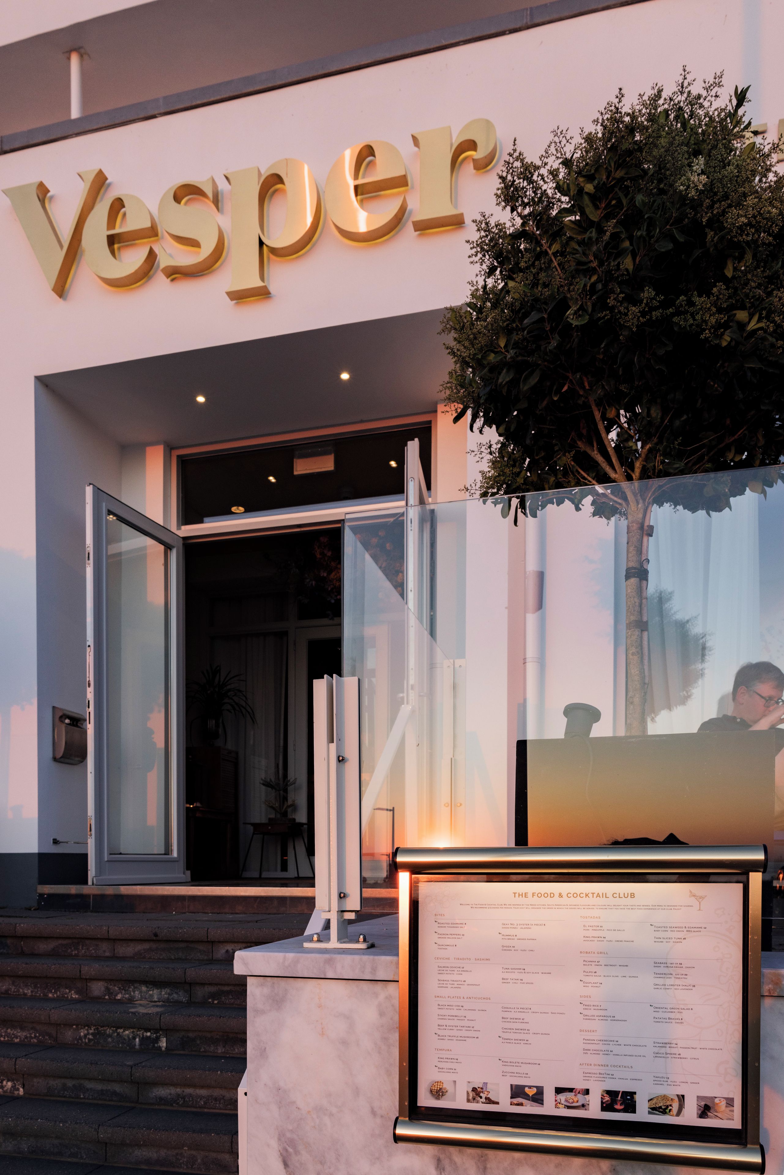 L’extérieur d’un bâtiment, avec une grande enseigne sur laquelle on peut lire « Yesper » et un panneau affichant le menu devant l’entrée.