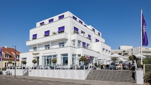A white building with a sign reading "Vesper The Food & Cocktail Club" and outdoor seating.