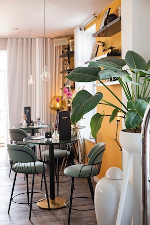 A dining area with a round table, chairs, and a potted plant. - Vesper Hotel (Noordwijk)