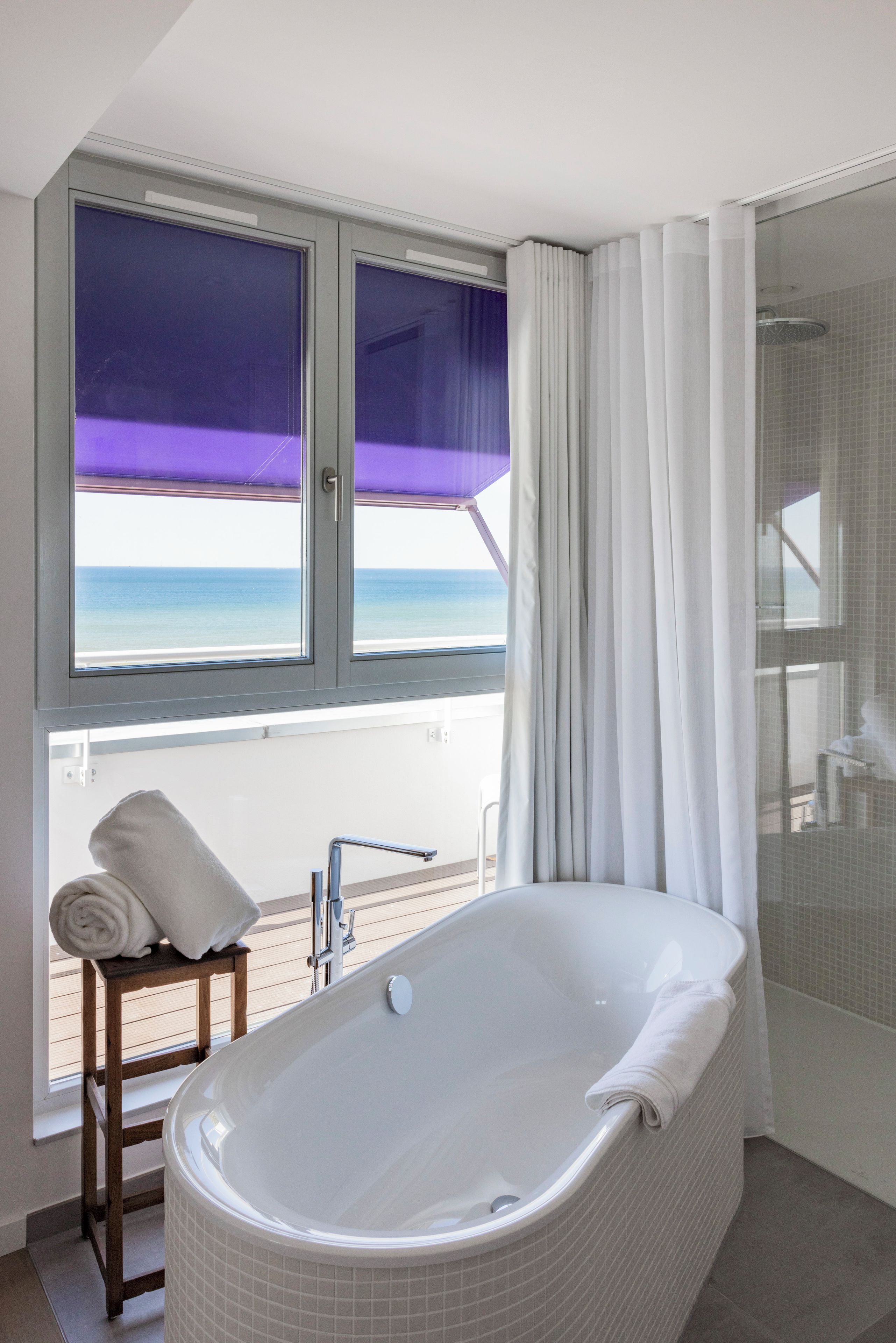 Un bagno con vasca, doccia e finestra vista mare.