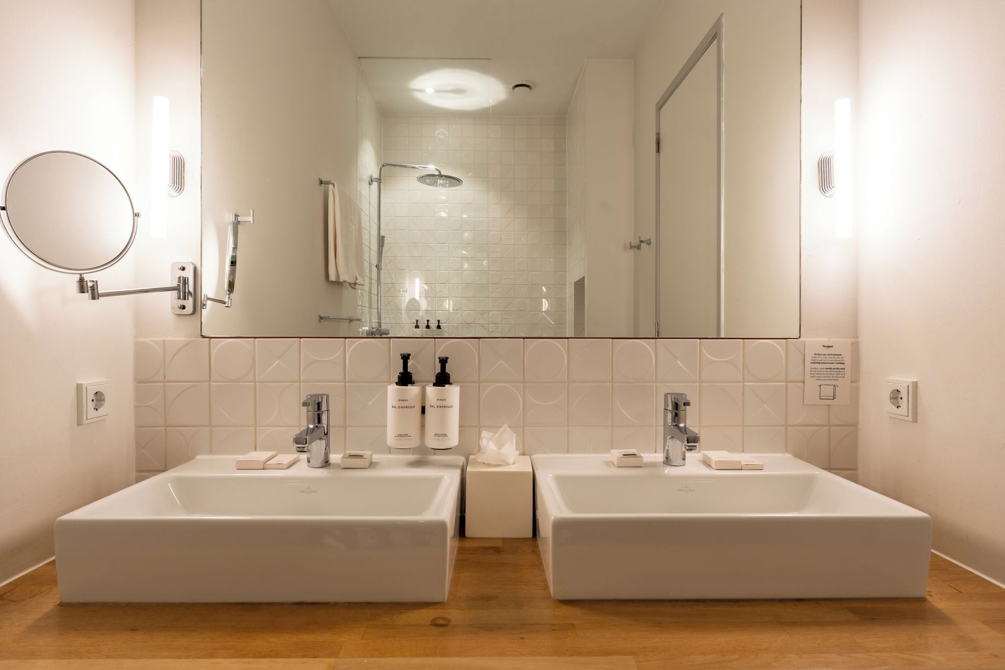 A bathroom with two sinks, a mirror, and a shower.