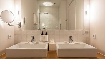 A bathroom with two sinks, a mirror, and a shower.