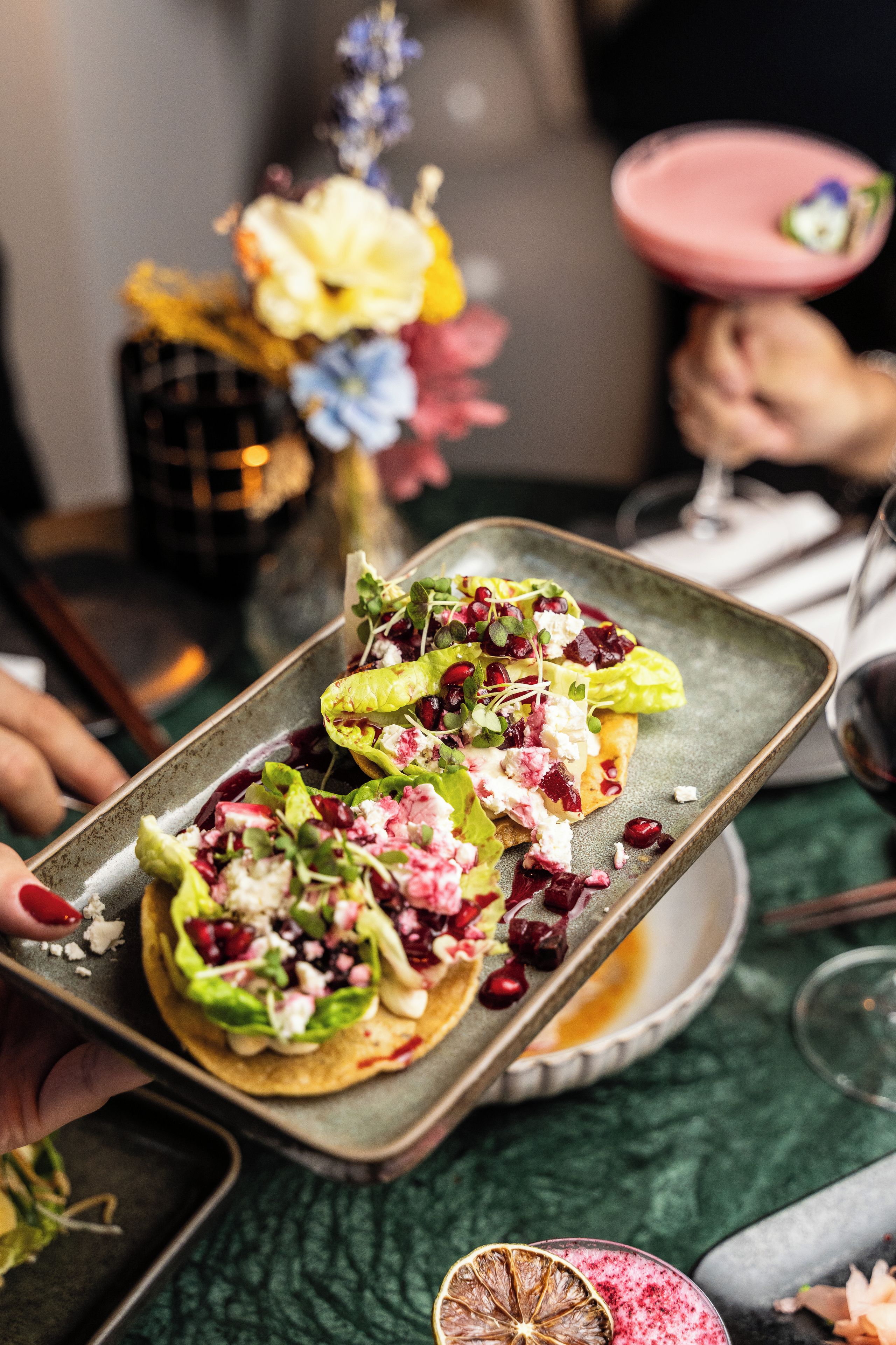 A tray with a salad on a plate, a glass of drink, and a dessert on a plate.