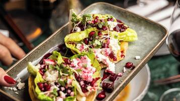 A tray with a salad on a plate, a glass of drink, and a dessert on a plate.