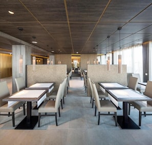 A modern hotel lobby with a central seating area, high ceilings, and a view of the lobby in the background. - My Hotel Olching  (Olching)