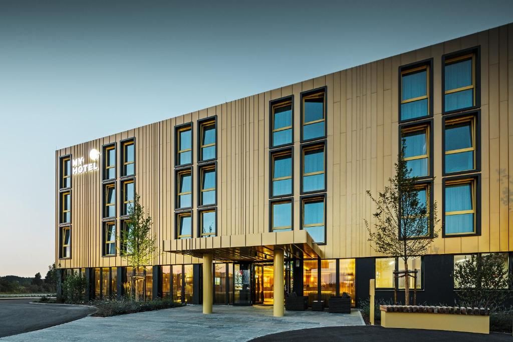 Un hôtel moderne à la façade sobre, doté de grandes fenêtres et d’un espace d’entrée abrité.