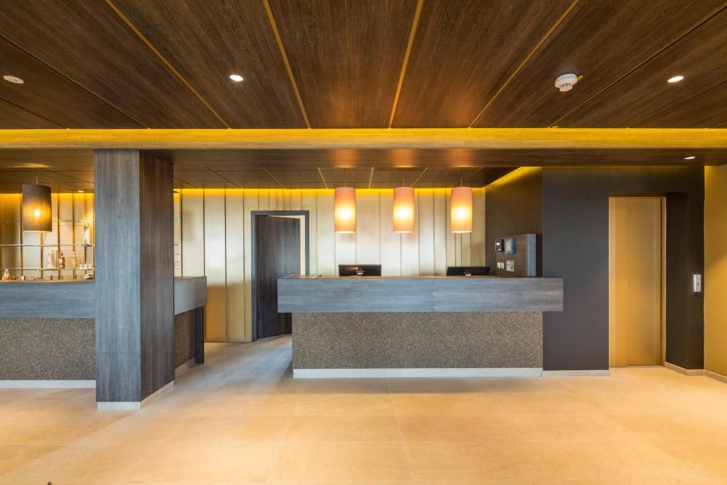 A reception area with a wooden ceiling, a reception desk, and pendant lighting.