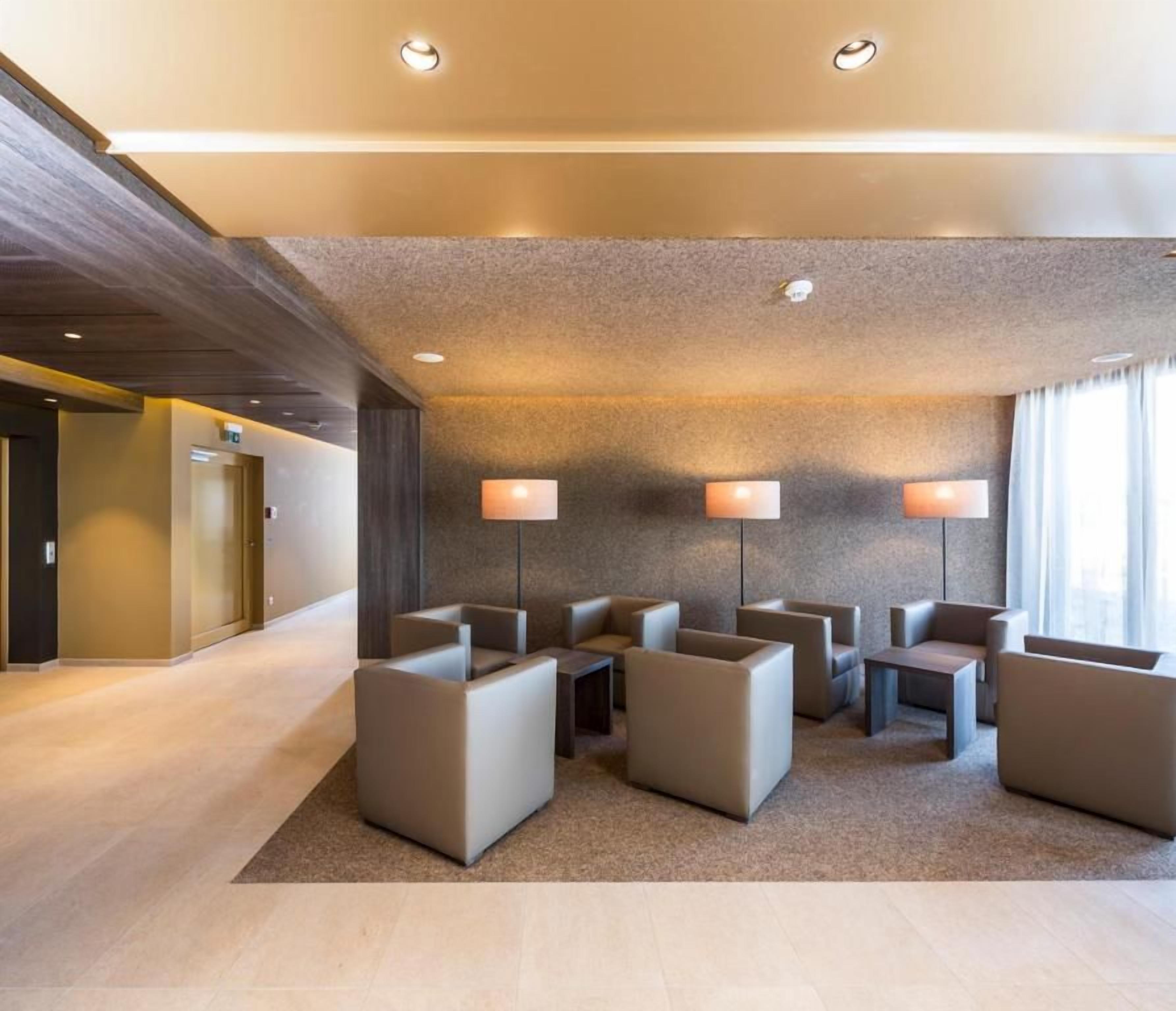 En hotellobby med en receptionsdisk, en sittgrupp med soffor och ett golv täckt av matta.