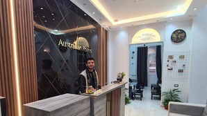 A reception area with a wooden reception desk, a sign reading "The Australian Hostel," and a clock on the wall. - The Australian Hostel (Cairo)