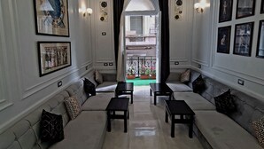 A spacious living room with a central sofa set, two side tables, and a view through a doorway to an outdoor balcony. - The Australian Hostel (Cairo)