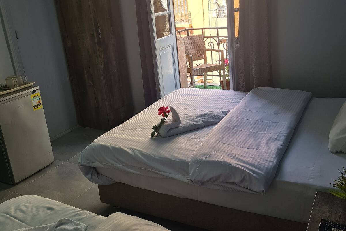Ein Hotelzimmer mit Bett, Sessel, kleinem Tisch und Kühlschrank.