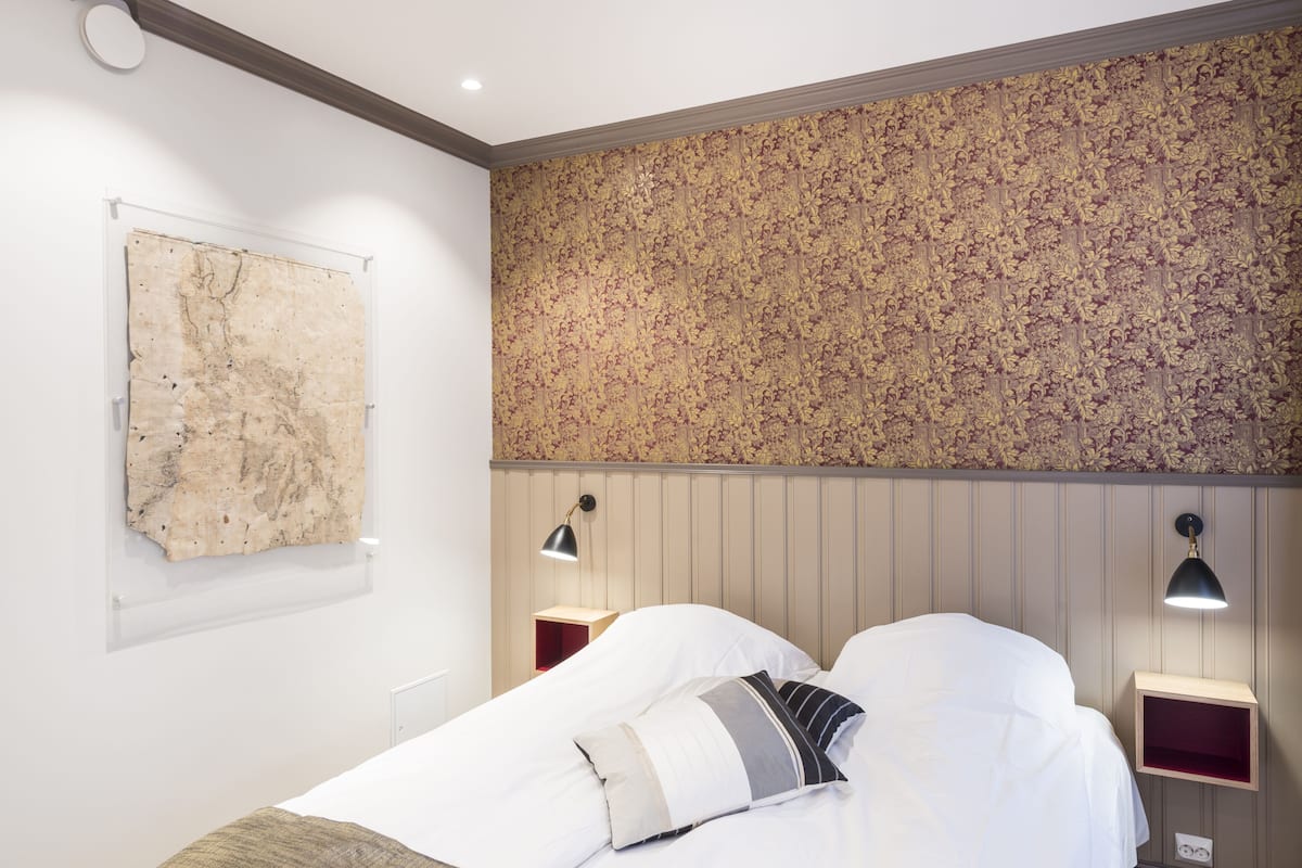 Habitación de hotel con cama, una obra de arte colgada en la pared y un panel decorativo.