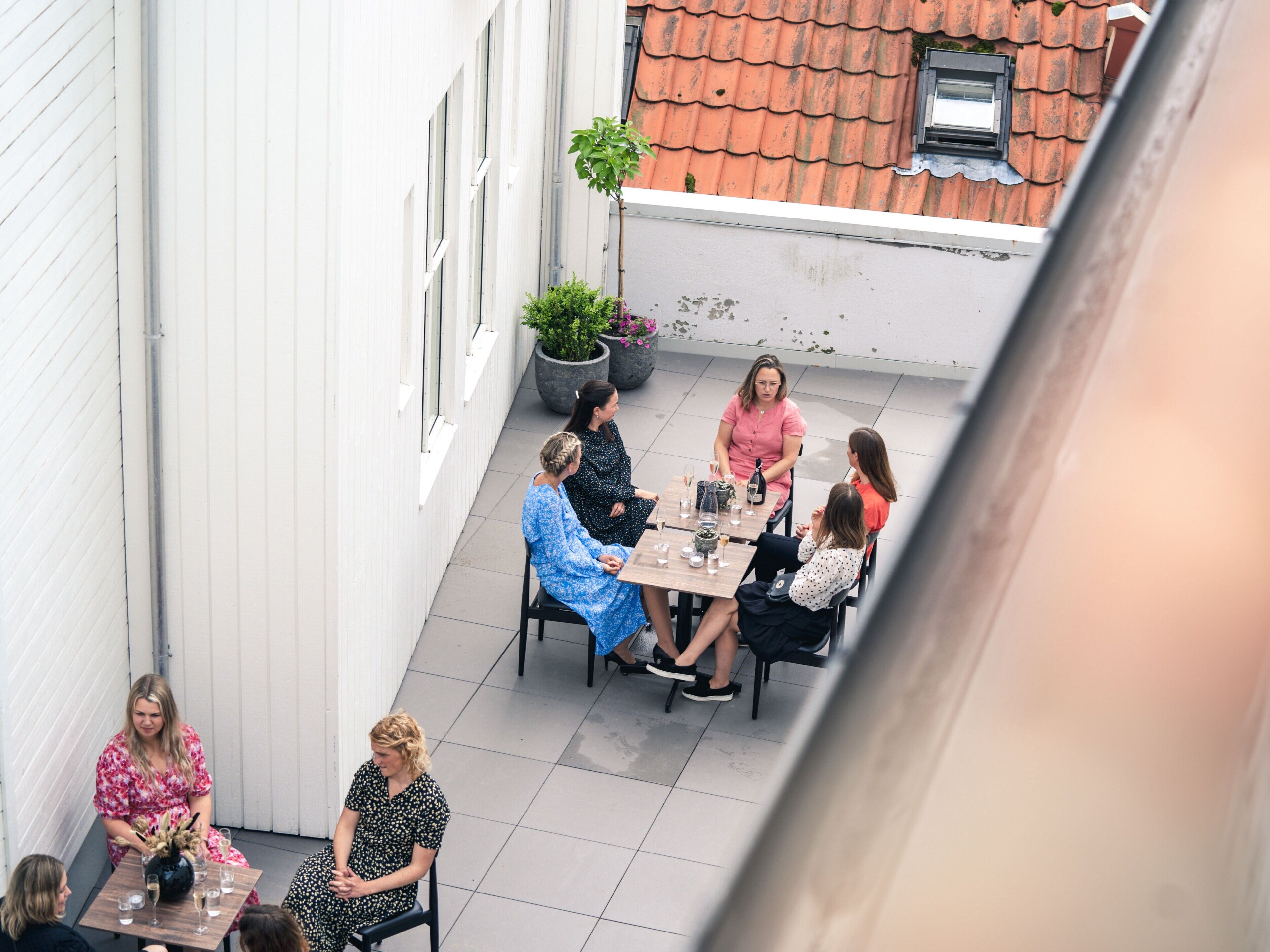 A group of people seated at an outdoor table with a view of a building's exterior.
