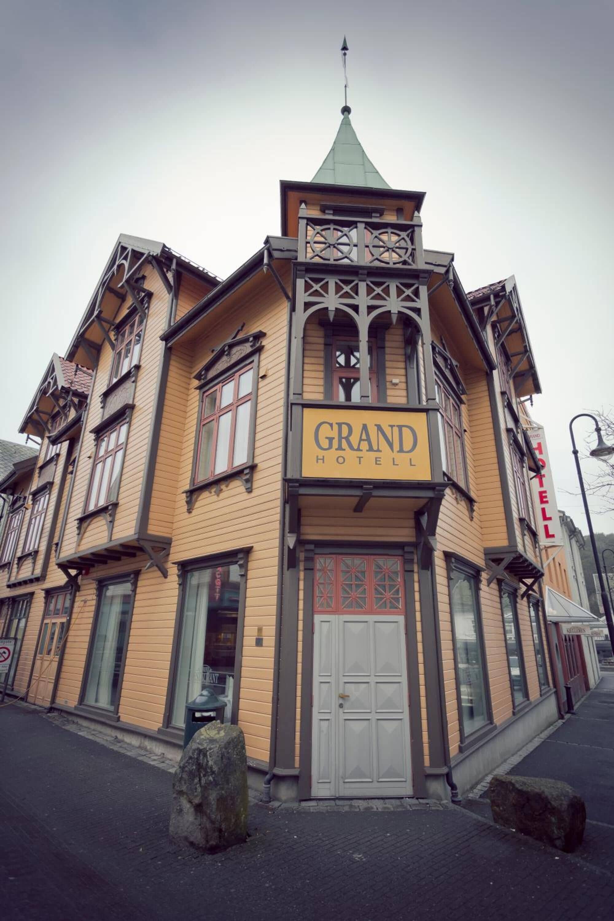 Un edificio con un letrero que dice "GRAND HOTEL" y un estilo arquitectónico tradicional con techo verde y múltiples ventanas.