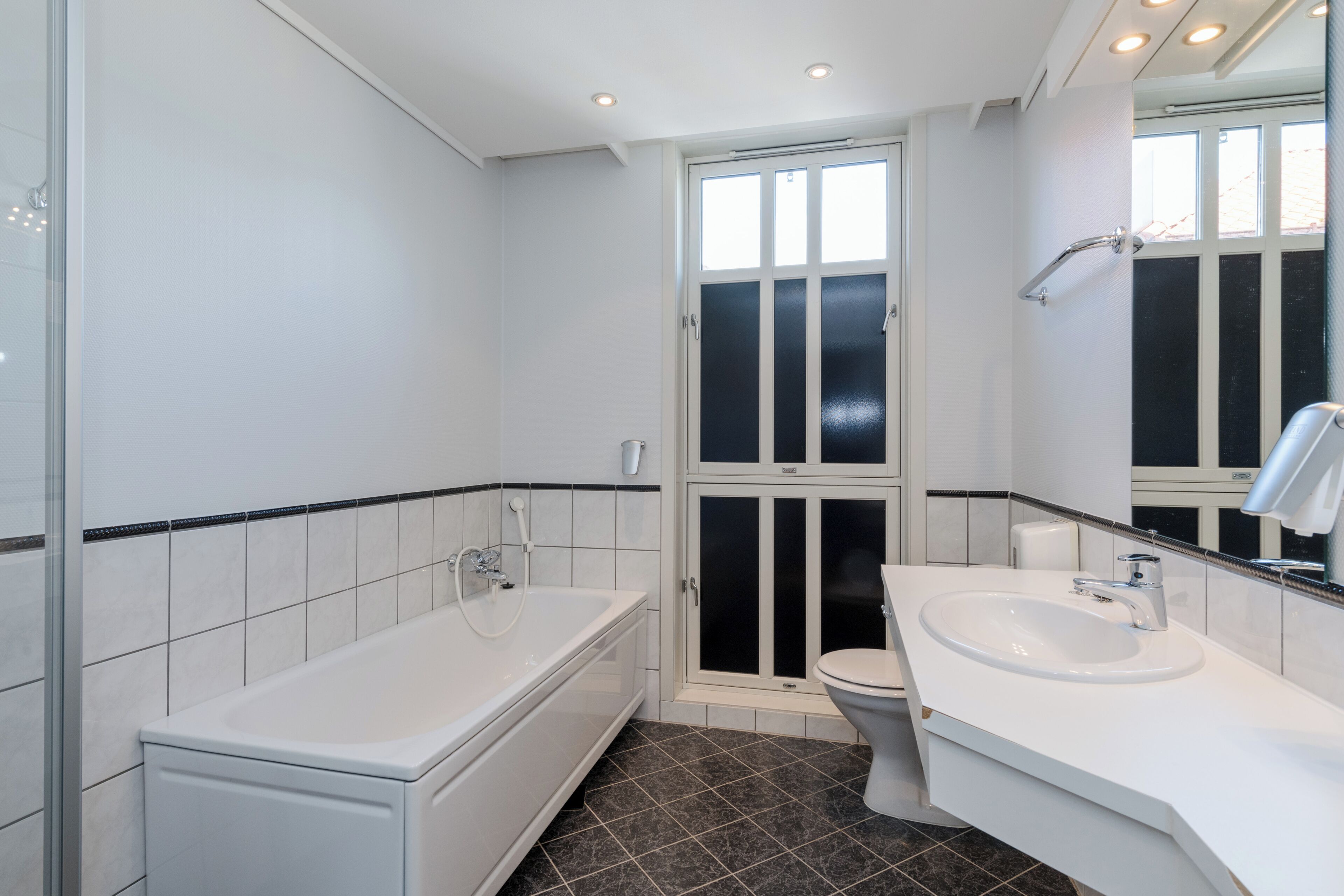 A modern bathroom with a bathtub, toilet, and sink.