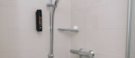 A shower with a handheld showerhead, a wall-mounted control panel, and a handheld shower hose.
