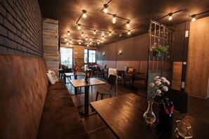 A restaurant interior with wooden tables, benches, hanging plants, and exposed brick walls. - Coffee Fellows Hotel München-Freiham (Munich)