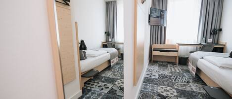 Habitación de hotel con dos camas, un escritorio, un televisor y un suelo con diseño.