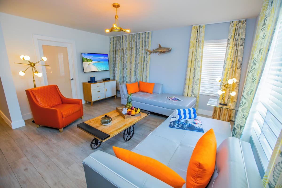 A modern living room with a sofa, armchair, and a coffee table with fruit.