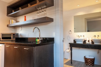 A modern kitchen with a washing machine, a microwave, and a sink. There is a teal door and orange shelves above the counter. at Seaside All Suites Hotel