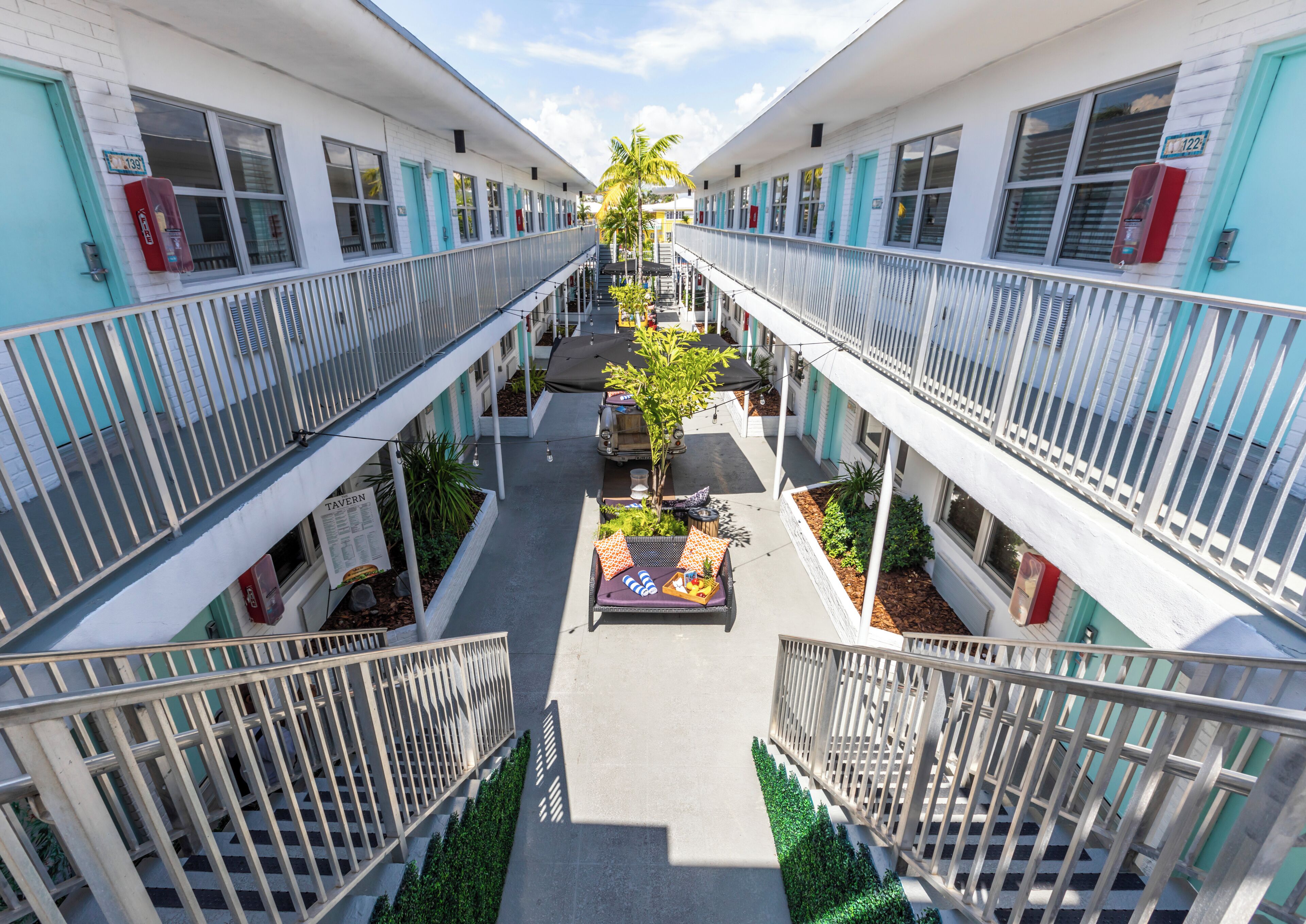 Un hôtel à plusieurs étages doté d’une cour intérieure aménagée avec des espaces de détente en plein air et des plantes.