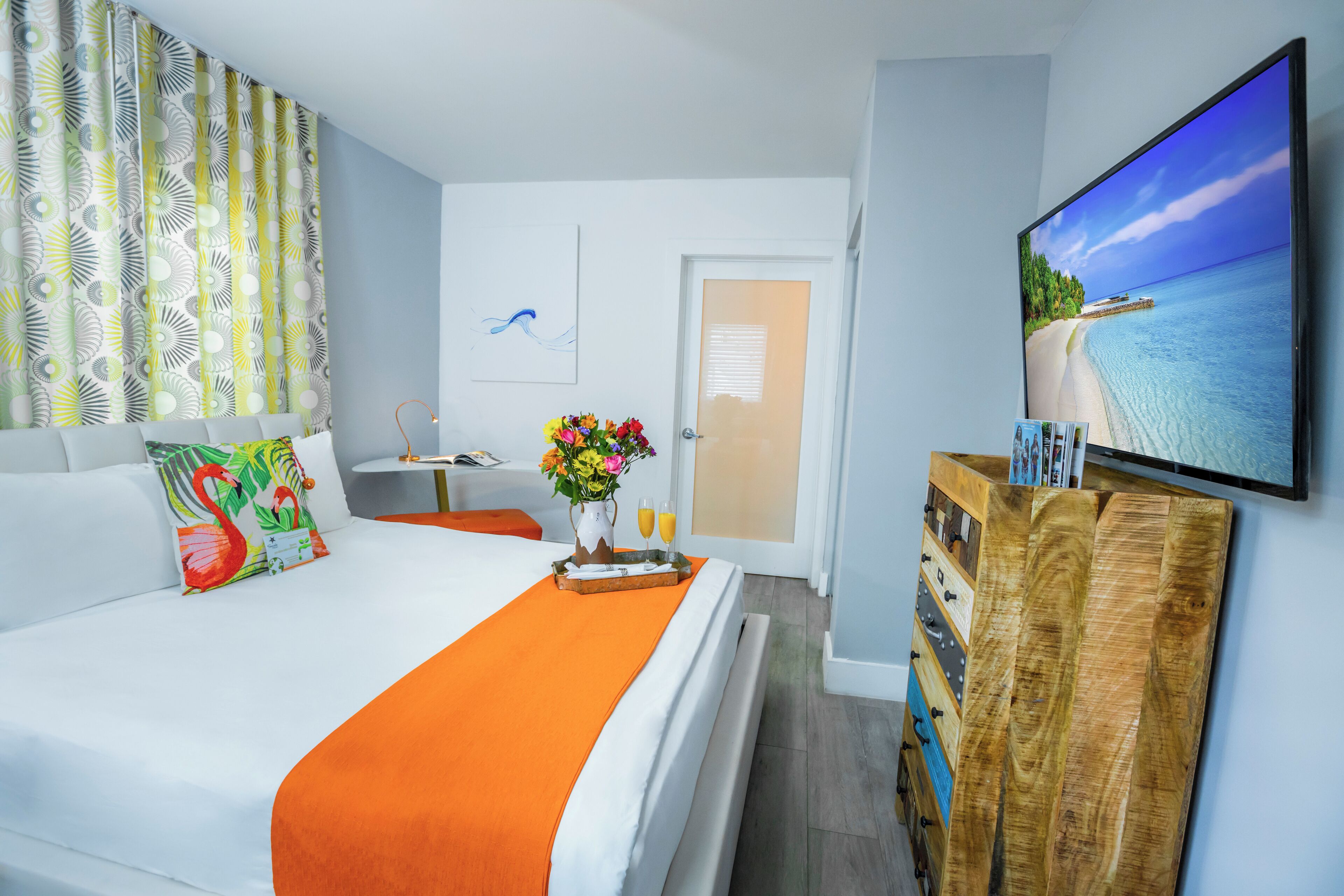 A hotel room with a bed, a TV, a wooden cabinet, and a door.