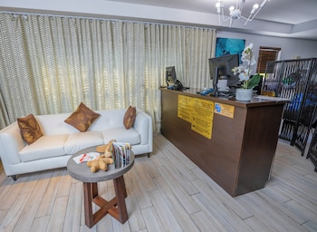 A compact kitchen with a washing machine, a microwave, and a coffee maker. There is a small dining area with a glass table and two yellow chairs. at Seaside All Suites Hotel